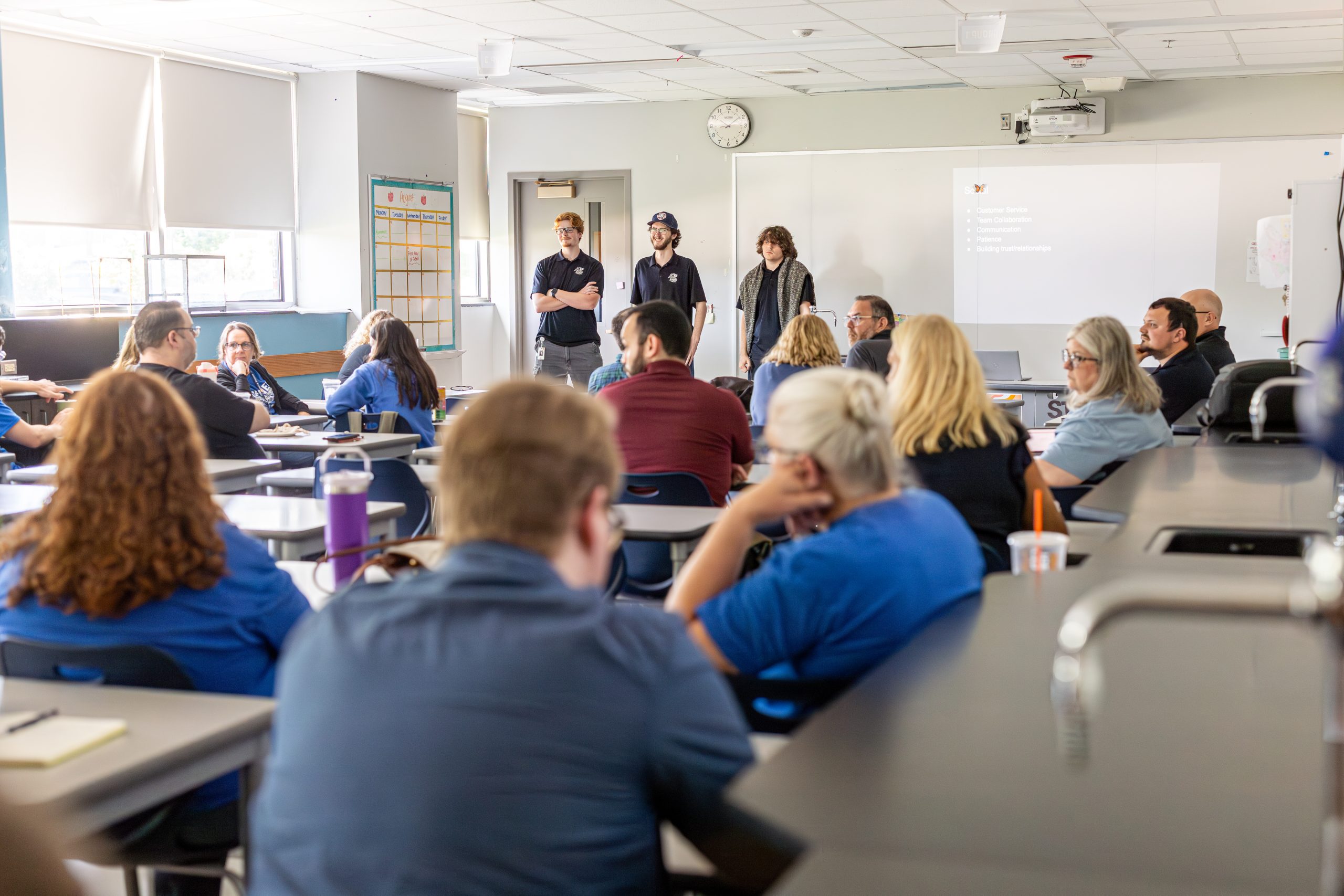 Three professionals presenting to a classroom full of attendees