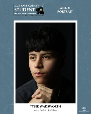 Close-up portrait of a person with dark hair looking thoughtfully to the side against a black background.