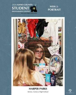Teen with glasses looks thoughtfully into a mirror surrounded by colorful bows and personal items on a vanity.