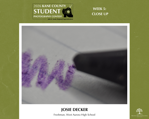 Zoomed in shot of a purple crayon doodling on lined paper