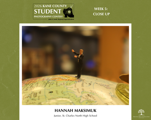A tiny action figure stands on top of a globe